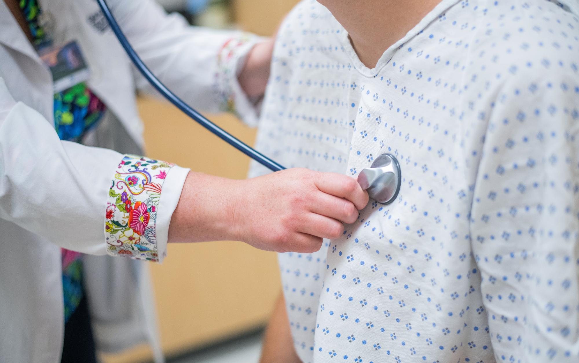 Nursing student using a stethoscope to check standardized patient's heartrate in a simulation setting